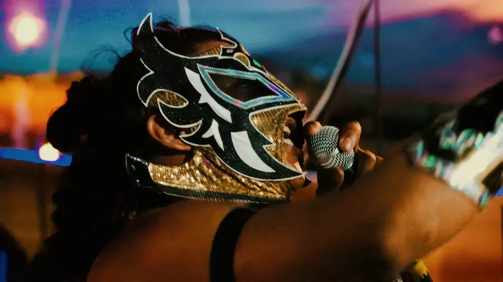 Luchador enmascarado apoyado en las cuerdas del ring al atardecer